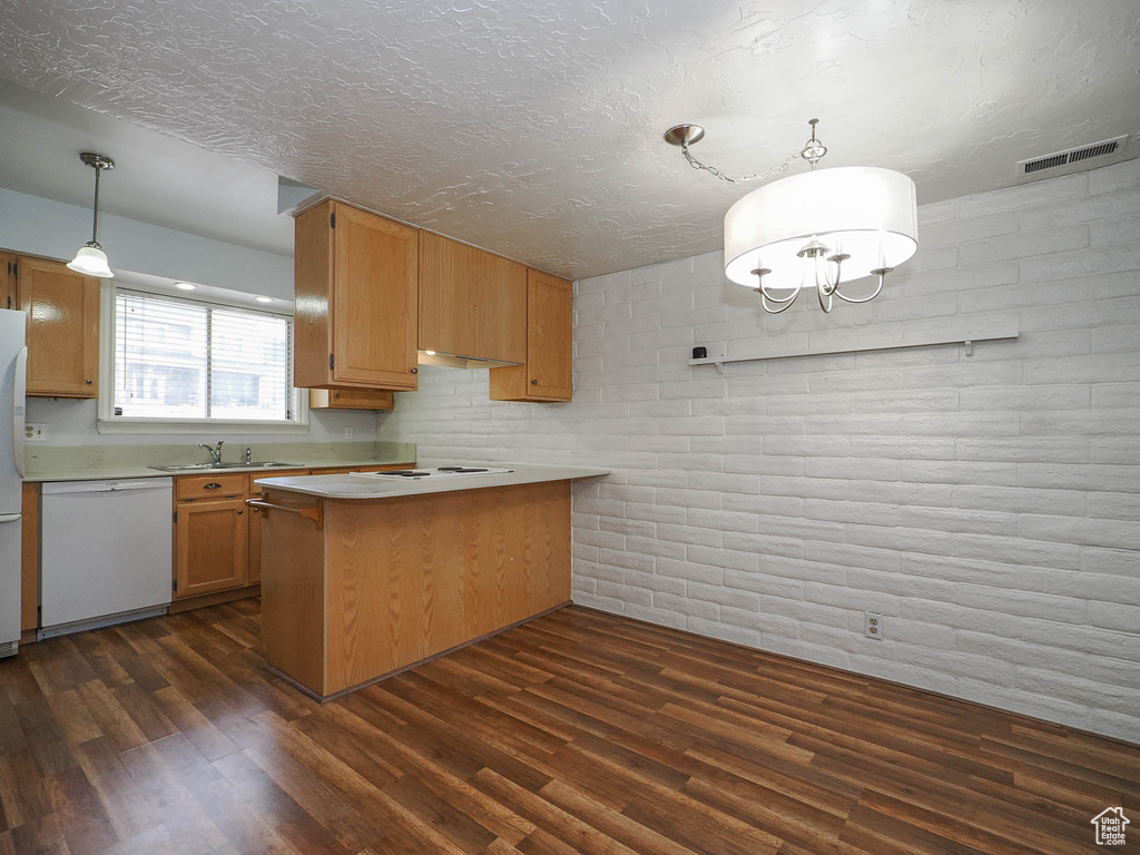 Kitchen featuring dark hardwood / wood-style flooring, sink, decorative light fixtures, white appliances, and kitchen peninsula