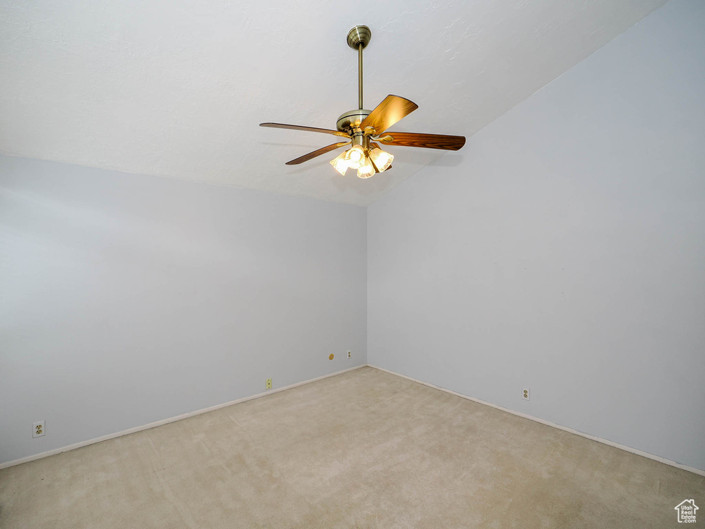 Empty room featuring vaulted ceiling, ceiling fan, and light colored carpet