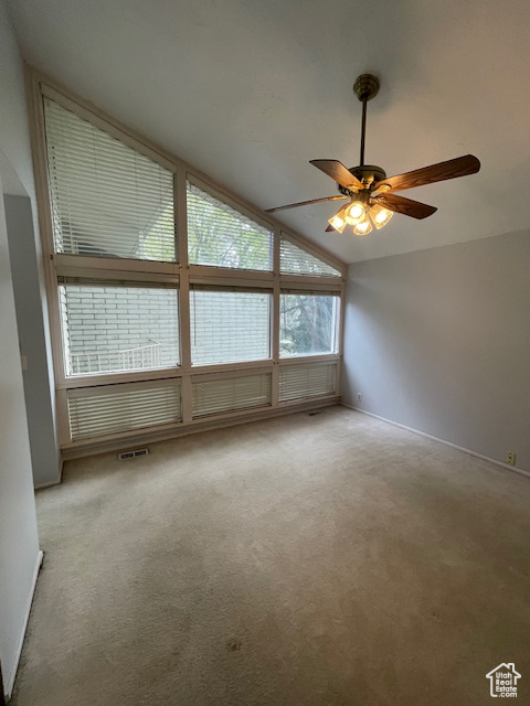 Spare room with lofted ceiling, ceiling fan, and carpet