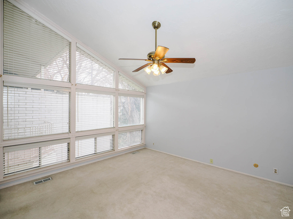 Carpeted empty room featuring ceiling fan and high vaulted ceiling