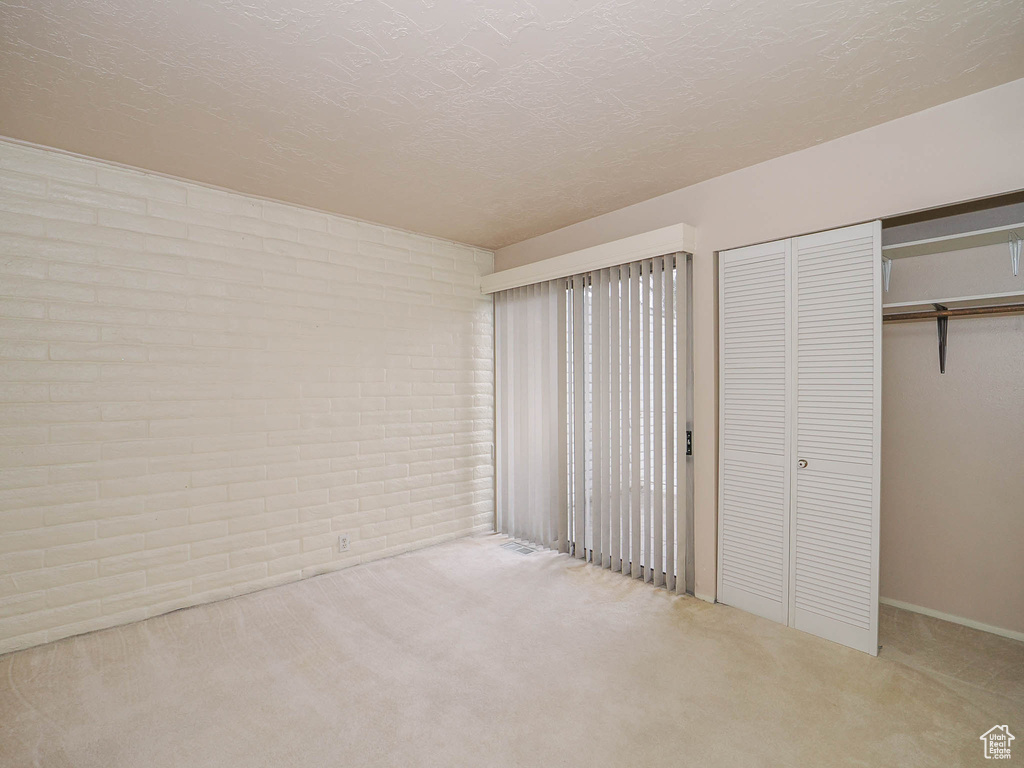 Unfurnished bedroom featuring light carpet, a textured ceiling, and a closet