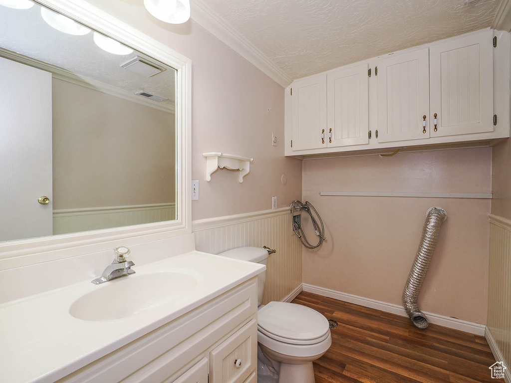 Bathroom featuring vanity, toilet, ornamental molding, and hardwood / wood-style flooring