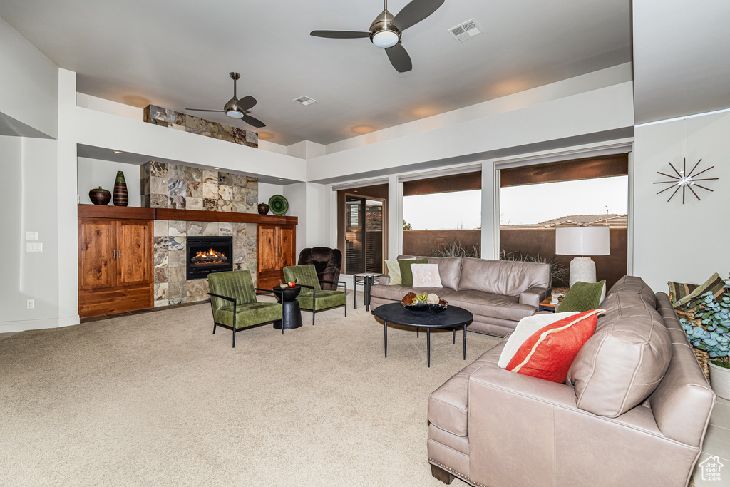 Living room featuring a fireplace, ceiling fan, and light carpet