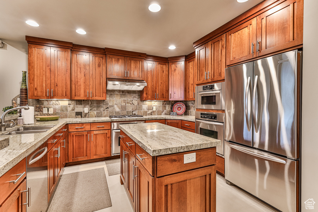 Kitchen featuring light stone countertops, backsplash, appliances with stainless steel finishes, sink, and light tile floors