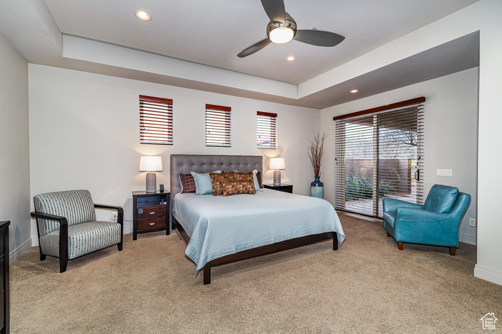 Bedroom with light carpet, ceiling fan, and a tray ceiling