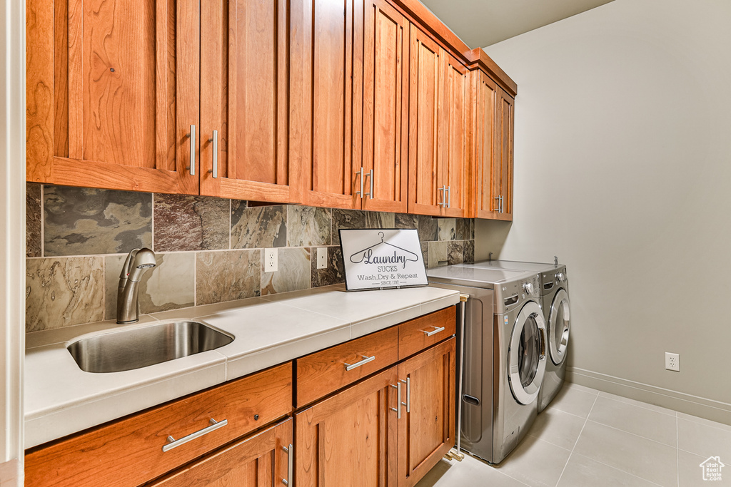 Laundry room with cabinets, light tile flooring, sink, and independent washer and dryer