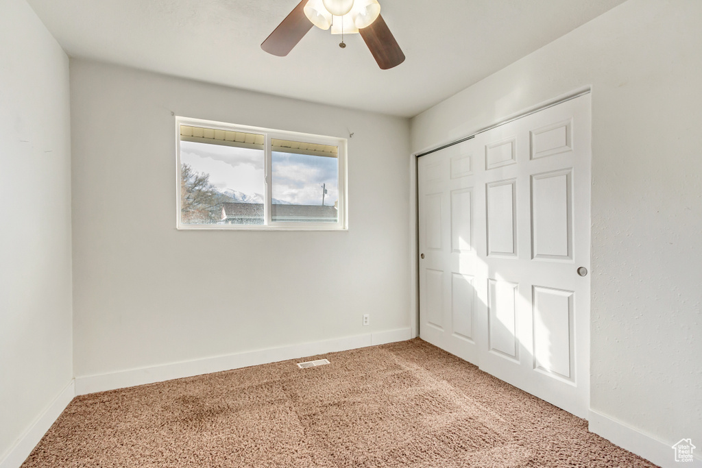 Unfurnished bedroom with a closet, ceiling fan, and light carpet