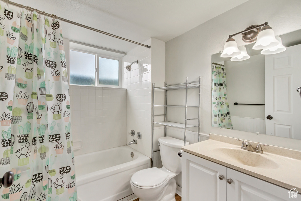 Full bathroom with large vanity, shower / bath combo with shower curtain, and toilet