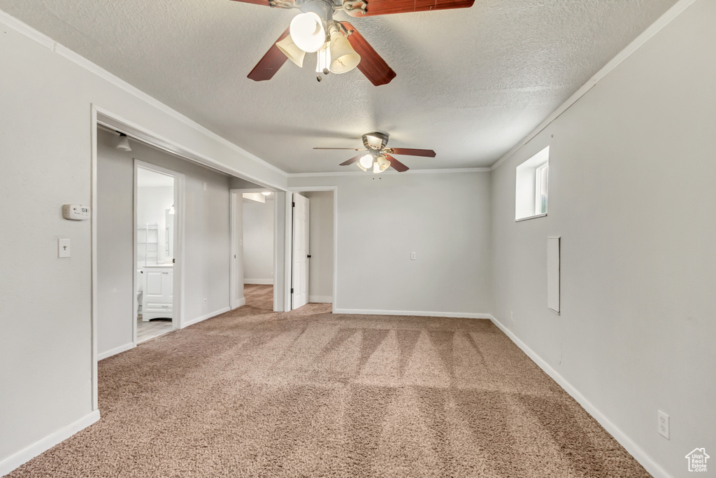 Empty room featuring ceiling fan, light colored carpet, and a textured ceiling