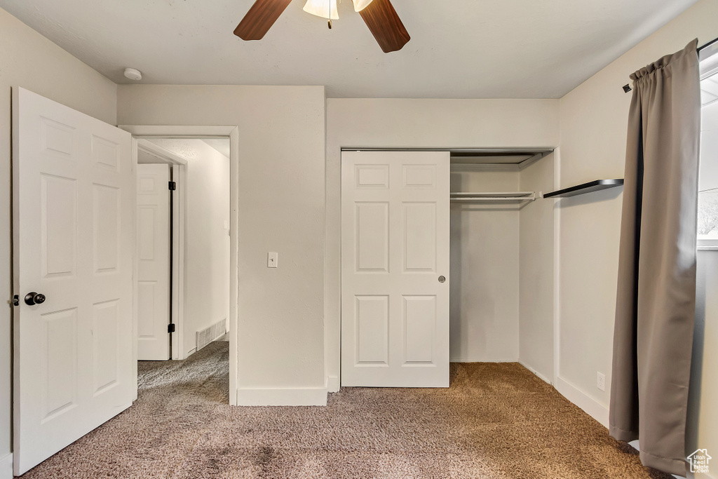Unfurnished bedroom with dark carpet, a closet, and ceiling fan