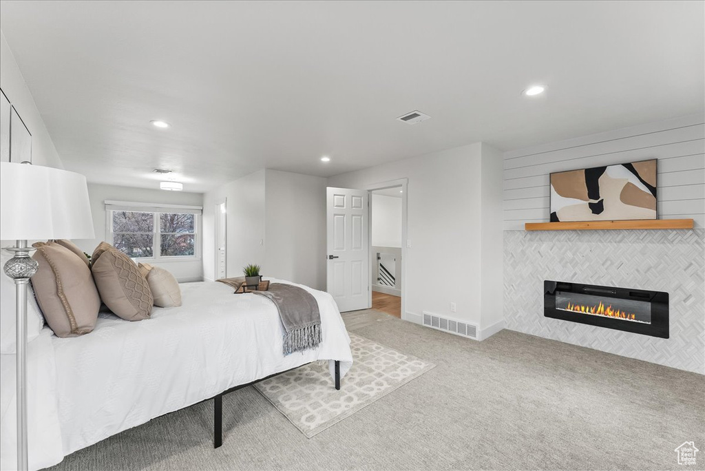 Bedroom with a fireplace and light carpet