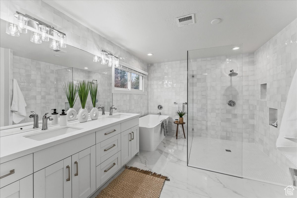 Bathroom with tile walls, tile floors, dual bowl vanity, and separate shower and tub