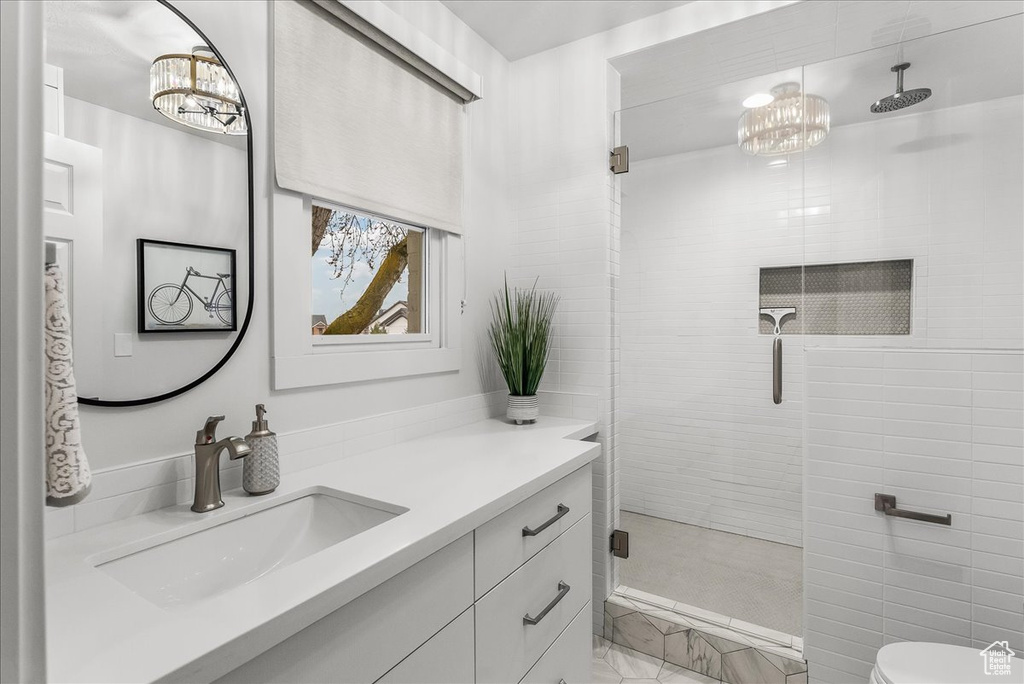 Bathroom featuring oversized vanity, tile walls, toilet, a shower with shower door, and tile flooring