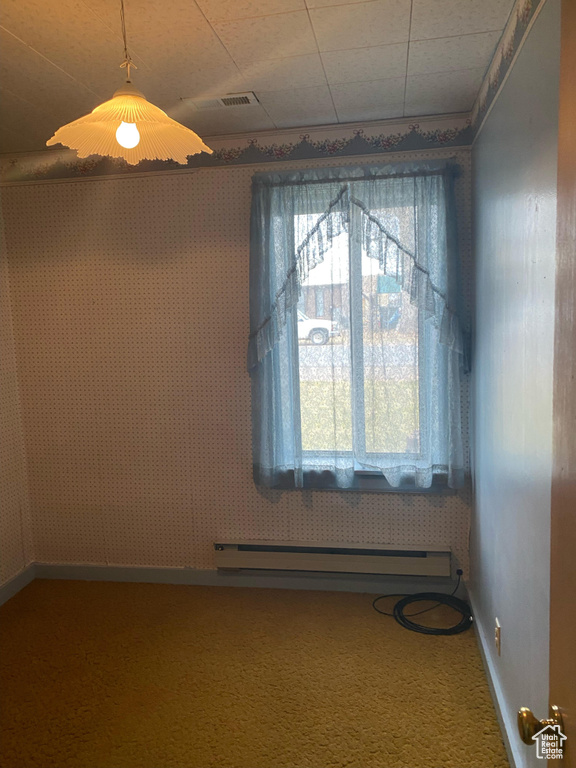 Unfurnished room featuring a wealth of natural light, a baseboard radiator, and carpet flooring