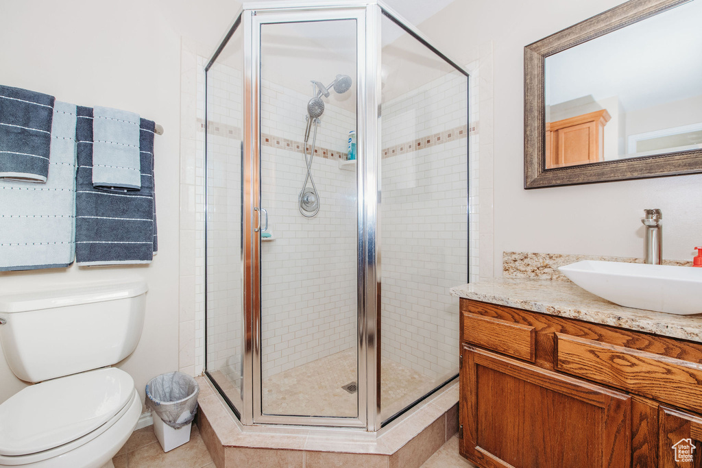 Bathroom featuring vanity, toilet, a shower with shower door, and tile flooring