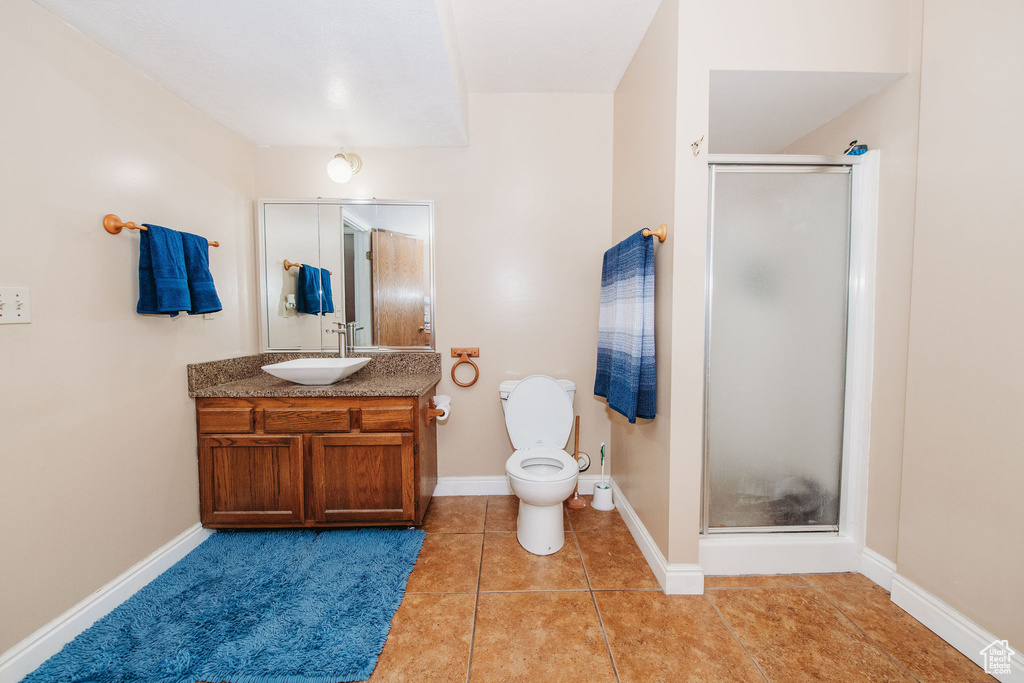 Bathroom featuring tile flooring, oversized vanity, walk in shower, and toilet