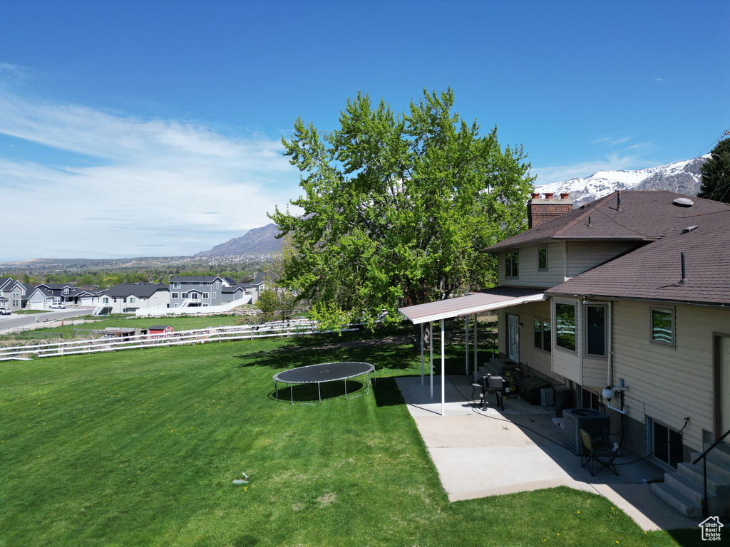 View of yard featuring a trampoline, central AC, a mountain view, and a patio area