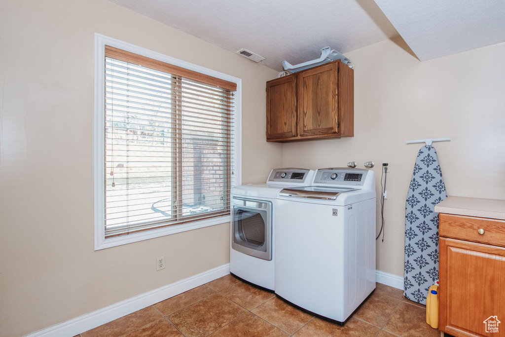 Washroom with light tile floors, separate washer and dryer, and cabinets