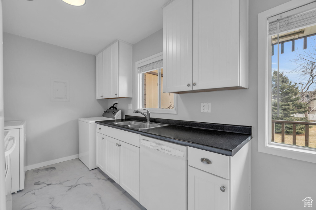 Kitchen featuring white dishwasher, white cabinetry, washing machine and dryer, sink, and light tile floors