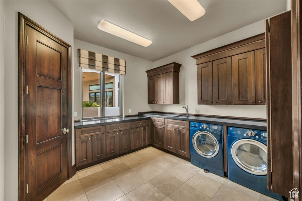 Laundry area featuring washing machine and clothes dryer, light tile floors, and cabinets