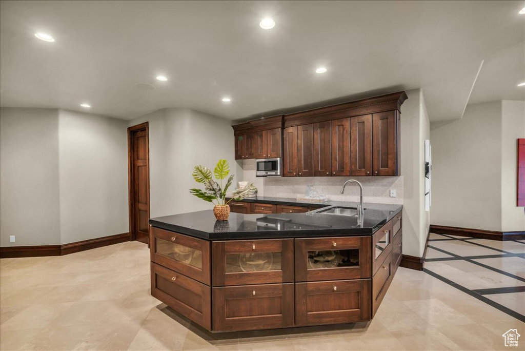 Kitchen with sink, light tile floors, backsplash, and stainless steel microwave