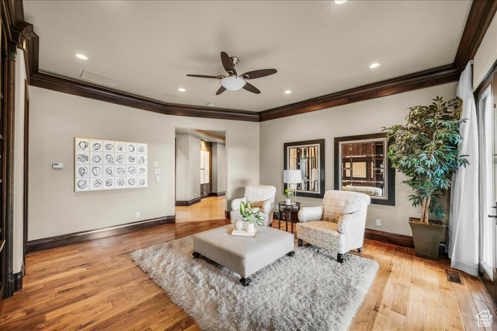 Living room featuring light wood-type flooring, a wealth of natural light, ceiling fan, and ornamental molding
