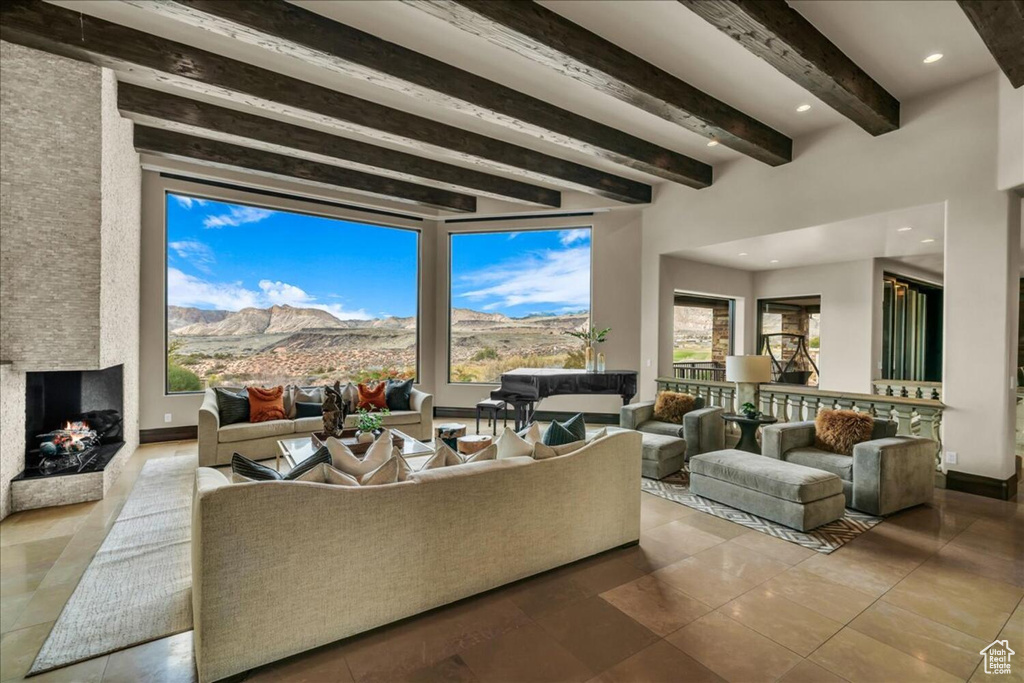 Living room with a mountain view, light tile floors, beam ceiling, and a large fireplace