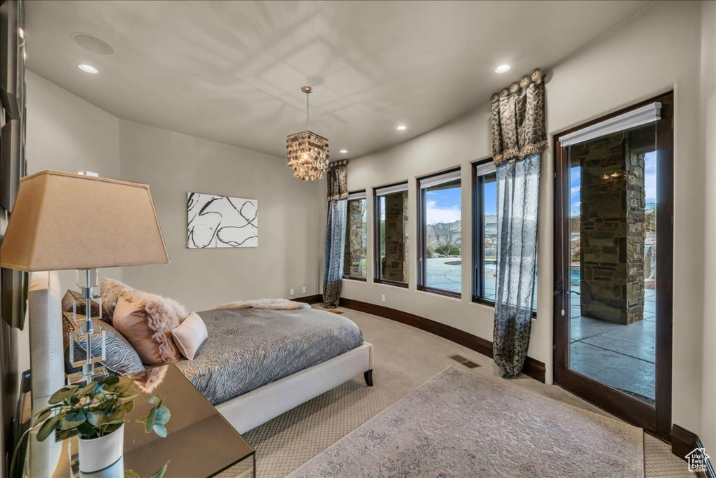 Carpeted bedroom featuring a notable chandelier and access to exterior