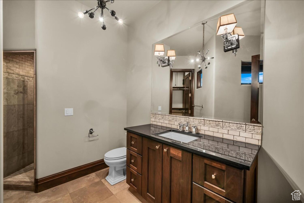 Bathroom with backsplash, tiled shower, vanity, toilet, and tile floors