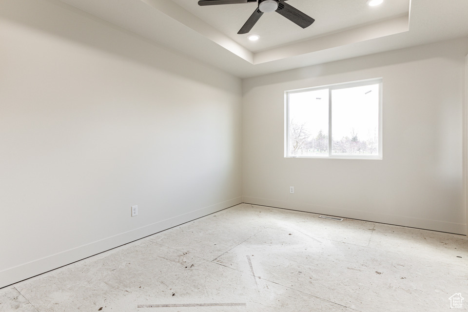Unfurnished room featuring ceiling fan and a tray ceiling