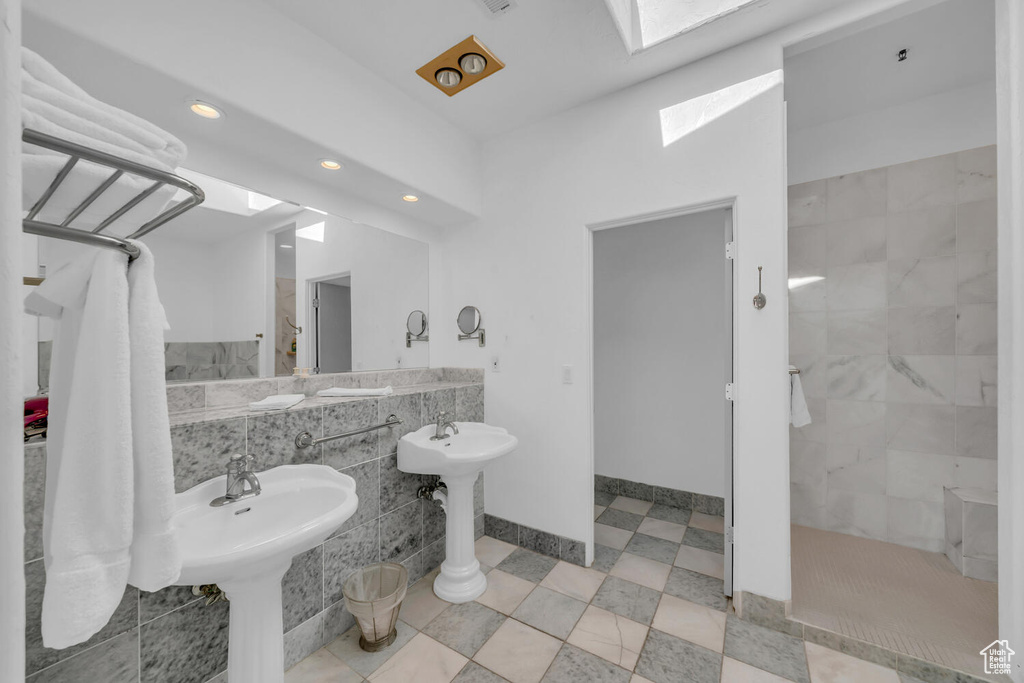 Bathroom featuring a skylight, tile walls, tile flooring, and a tile shower
