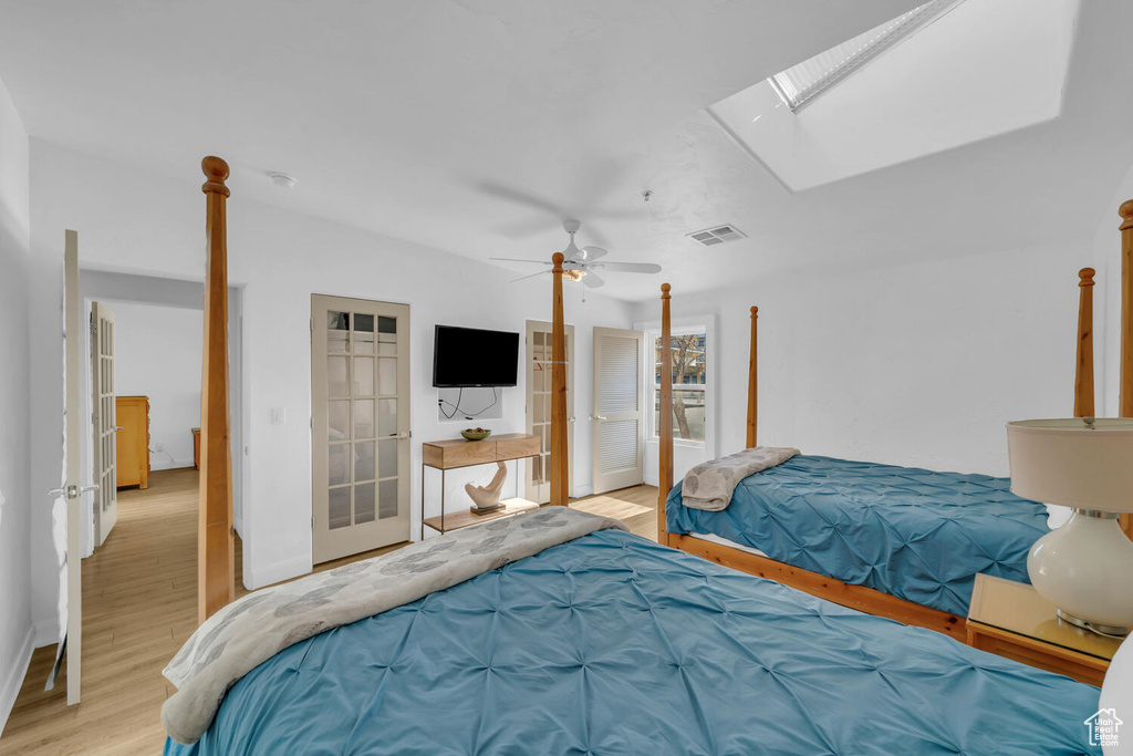 Bedroom with light hardwood / wood-style floors, a skylight, and ceiling fan