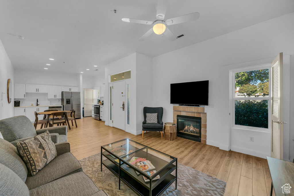 Living room featuring light hardwood / wood-style floors, a fireplace, and ceiling fan