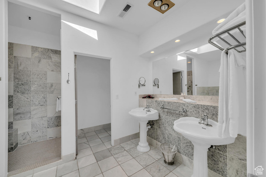 Bathroom with tile walls, a skylight, tiled shower, and tile flooring