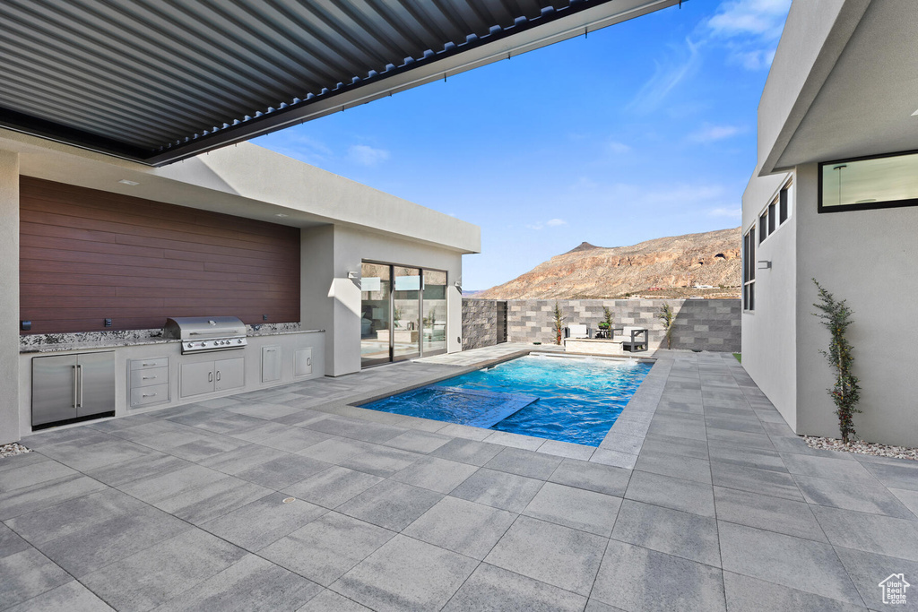 View of swimming pool featuring a mountain view, a patio, an outdoor kitchen, and grilling area
