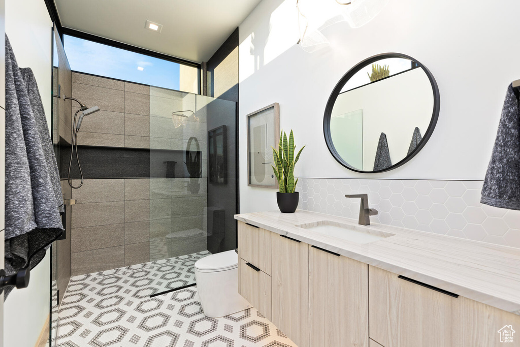 Bathroom featuring vanity, tasteful backsplash, a shower with shower door, and toilet