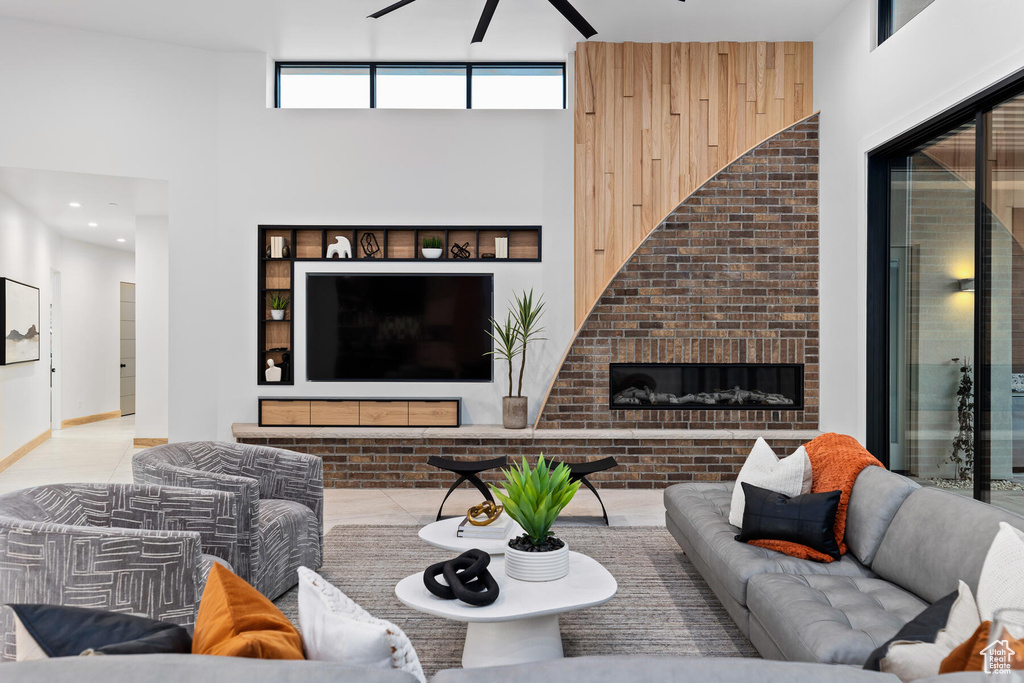 Tiled living room featuring wood walls, a high ceiling, and a brick fireplace