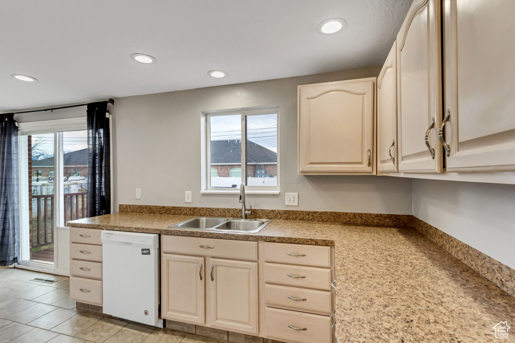 Kitchen featuring sink, white dishwasher, light tile floors, and a healthy amount of sunlight