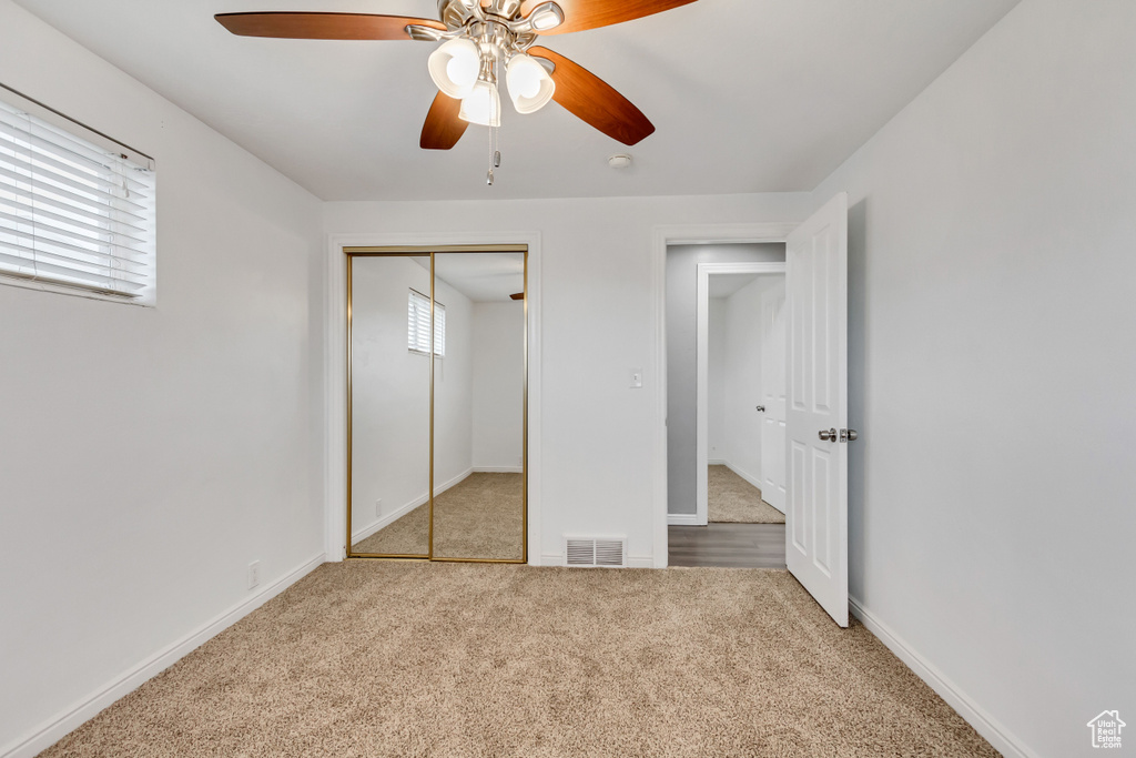 Unfurnished bedroom featuring a closet, ceiling fan, and light colored carpet