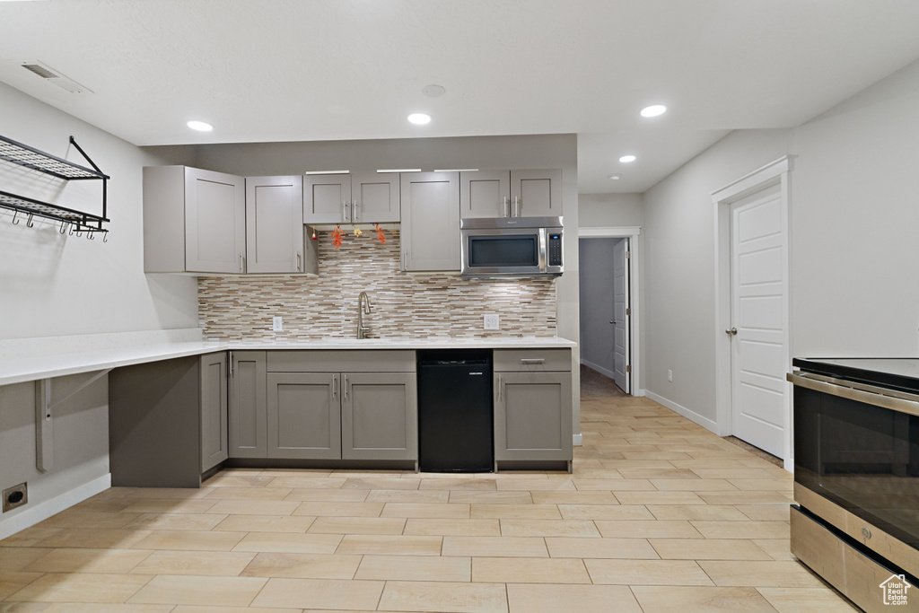 Kitchen with gray cabinets, dishwasher, and tasteful backsplash