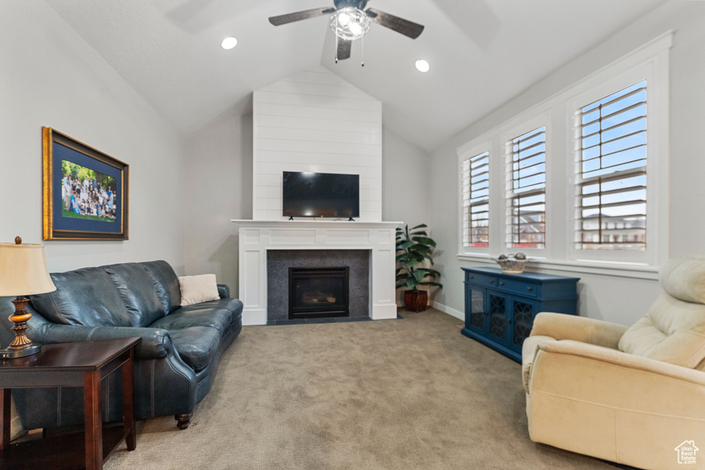 Carpeted living room featuring a fireplace, lofted ceiling, and ceiling fan