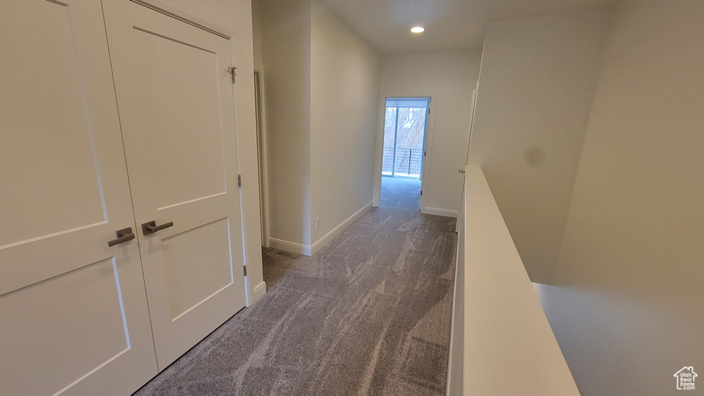 Corridor featuring dark colored carpet