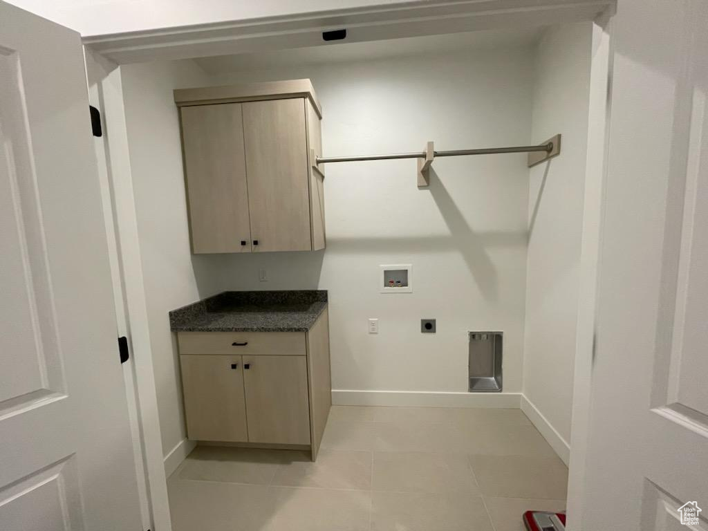 Clothes washing area with washer hookup, light tile flooring, cabinets, and hookup for an electric dryer