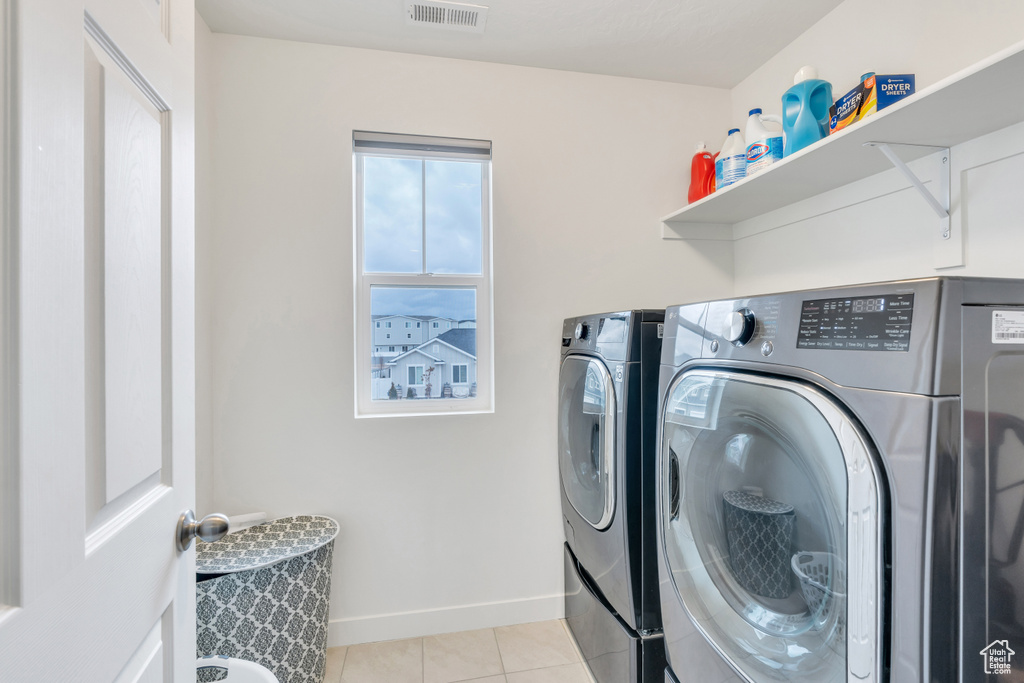Laundry room featuring light tile floors and separate washer and dryer