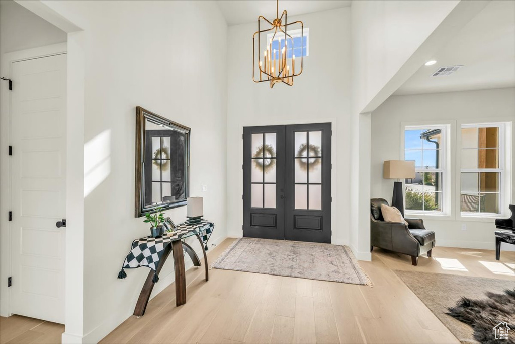 Entryway featuring an inviting chandelier, french doors, and light wood-type flooring