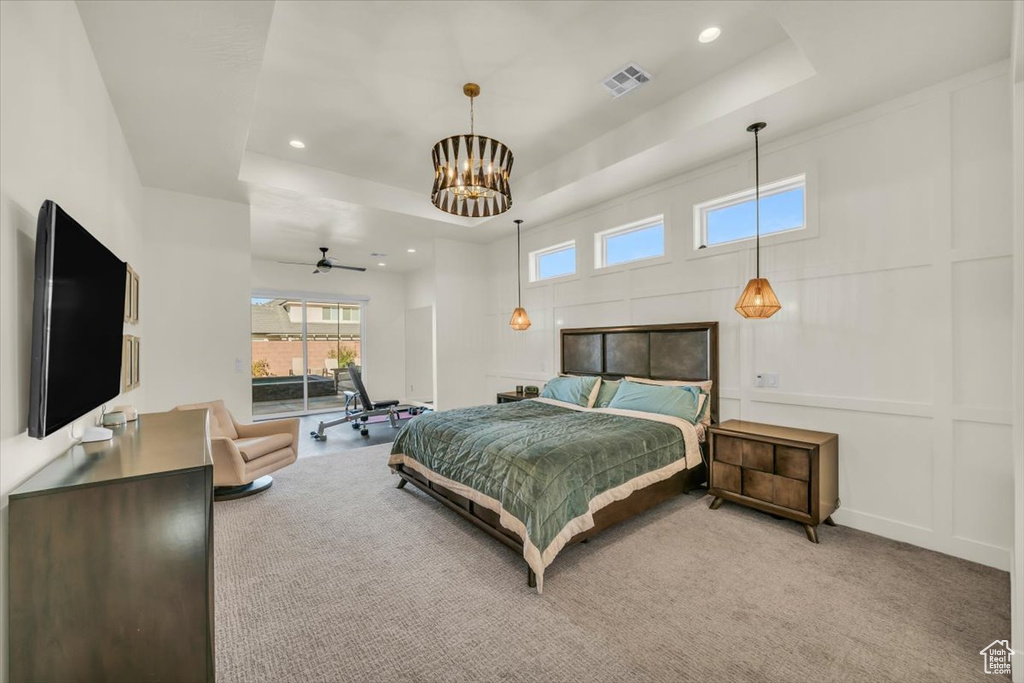 Carpeted bedroom featuring an inviting chandelier and a raised ceiling