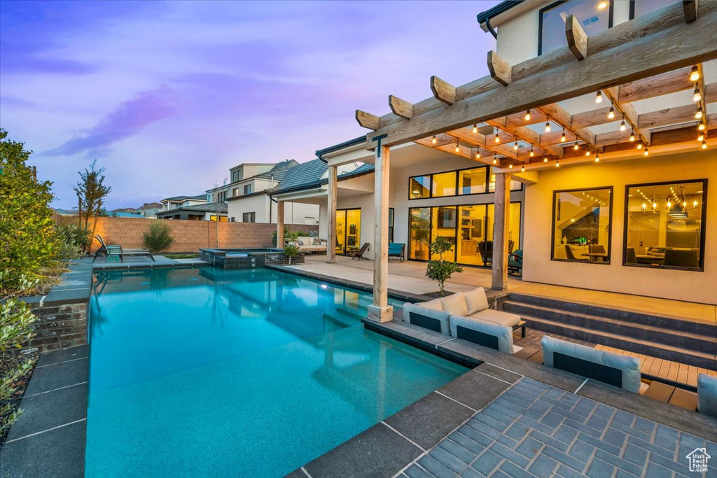 Pool at dusk with a pergola and a patio