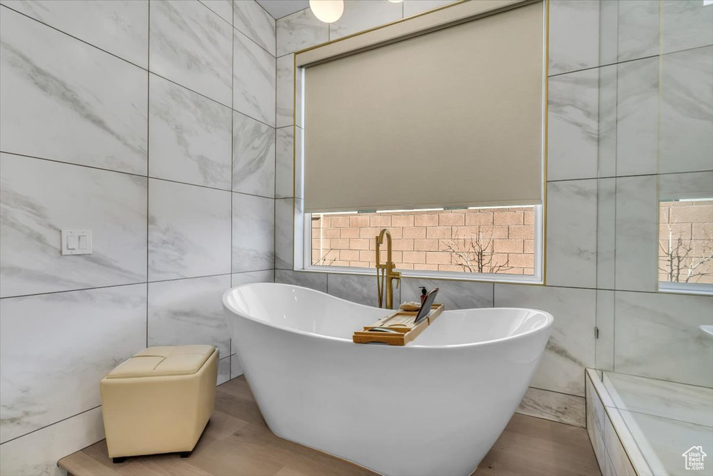 Bathroom with a wealth of natural light, tile walls, and a tub