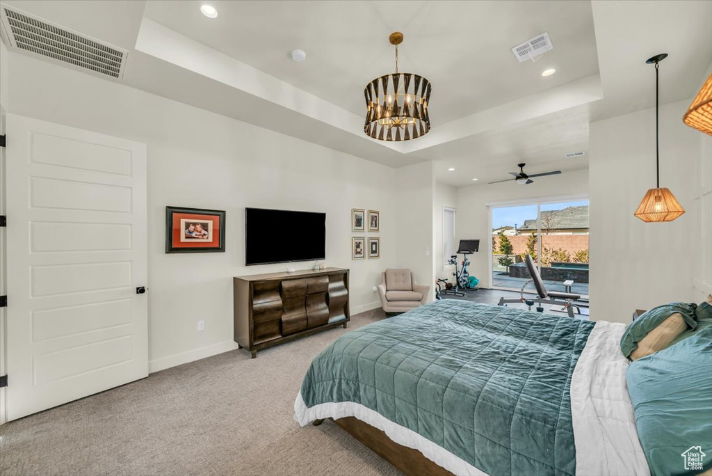 Bedroom featuring a chandelier, access to exterior, light colored carpet, and a raised ceiling
