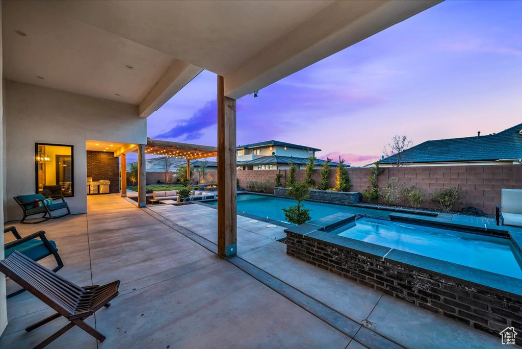Patio terrace at dusk featuring a pool with hot tub